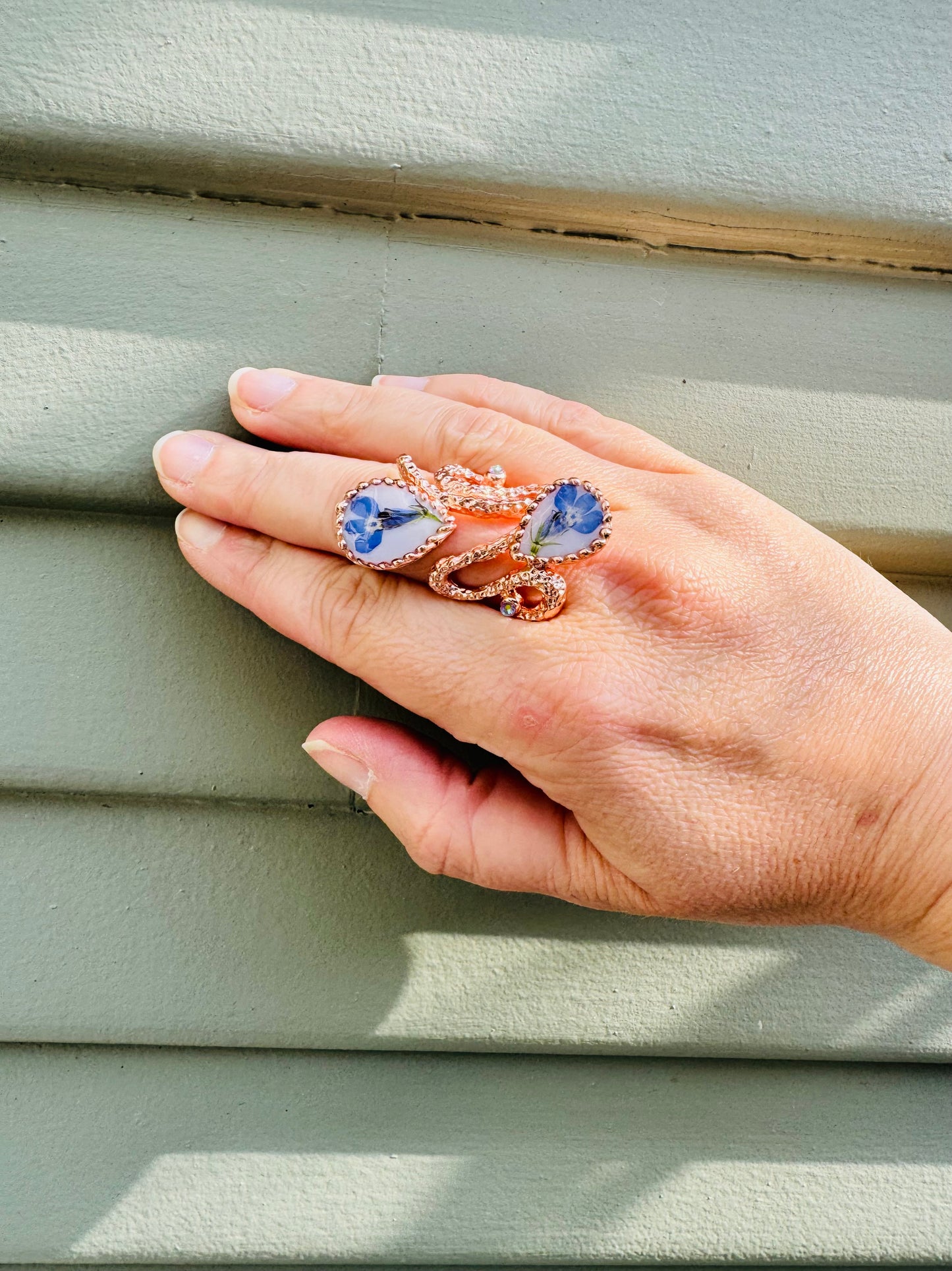 Oversized pink gold plated ring with blue flowers on a white background