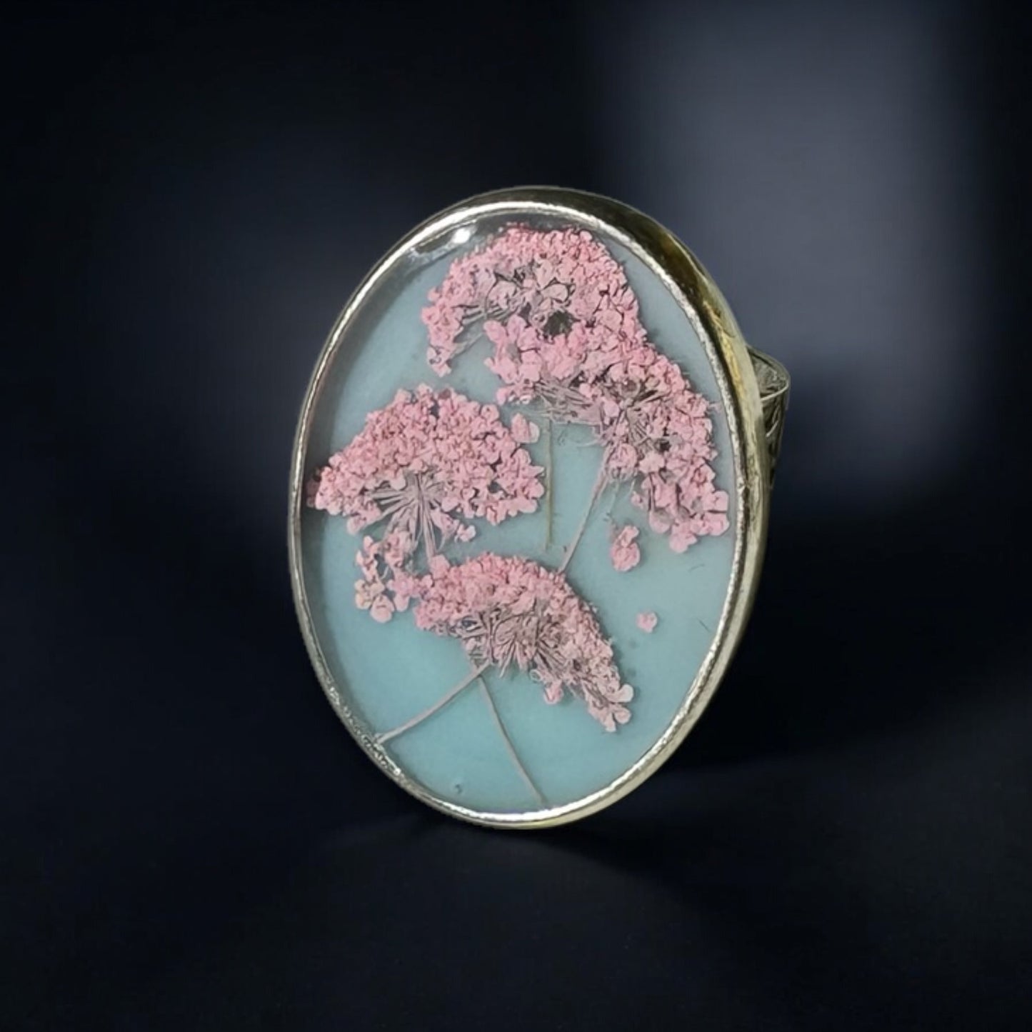 Oval ring with pink flowers on a blue background
