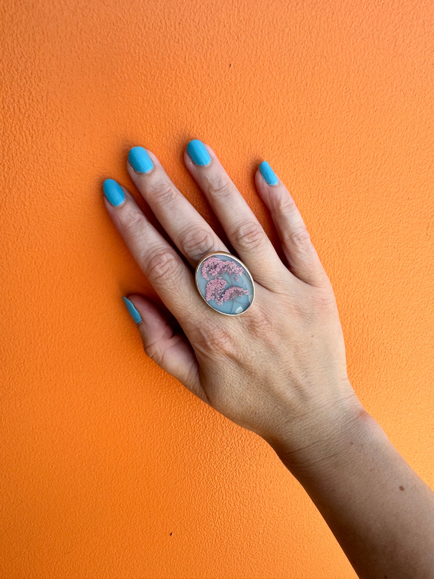 Oval ring with pink flowers on a blue background