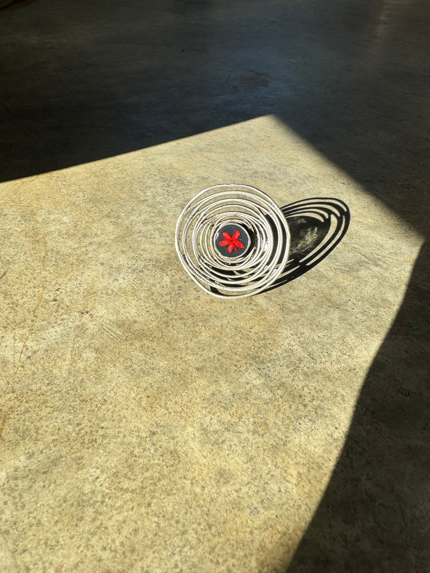 Oversized spiral silver ring with red flower on a navy background