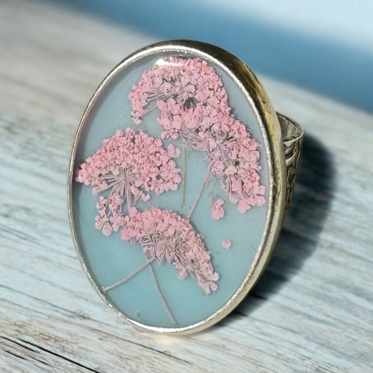 Oval ring with pink flowers on a blue background