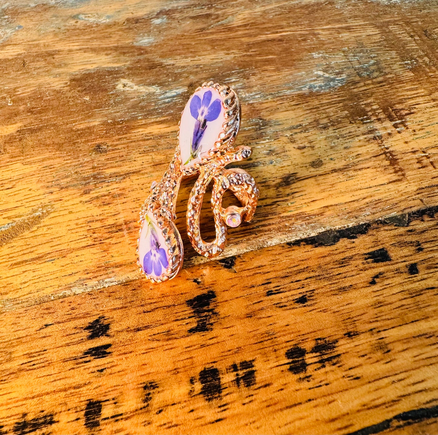 Oversized pink gold plated ring with blue flowers on a white background