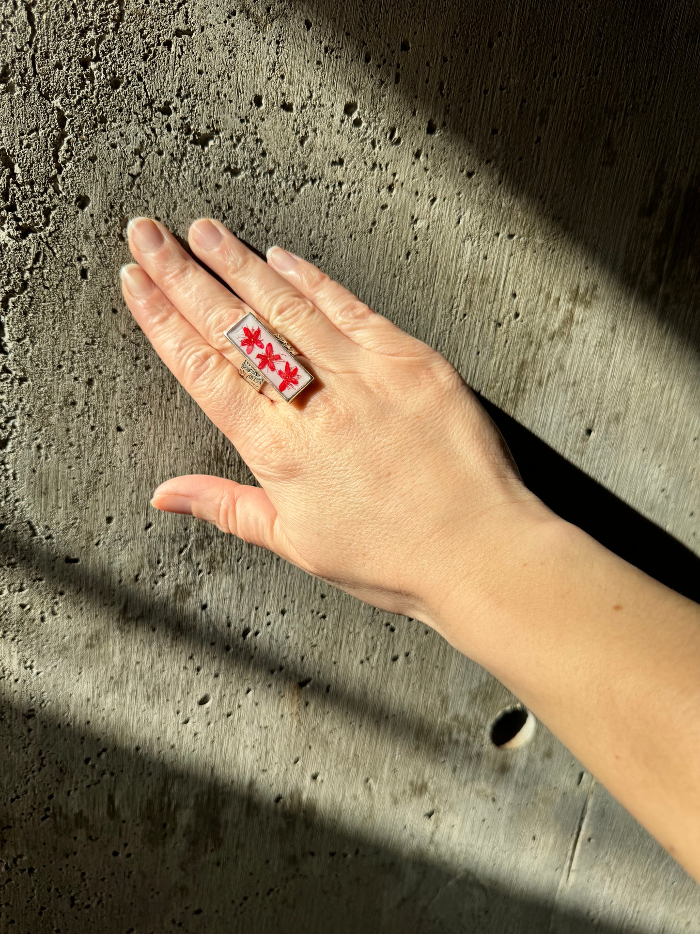 Rectangular long silver ring with red flower on a white background