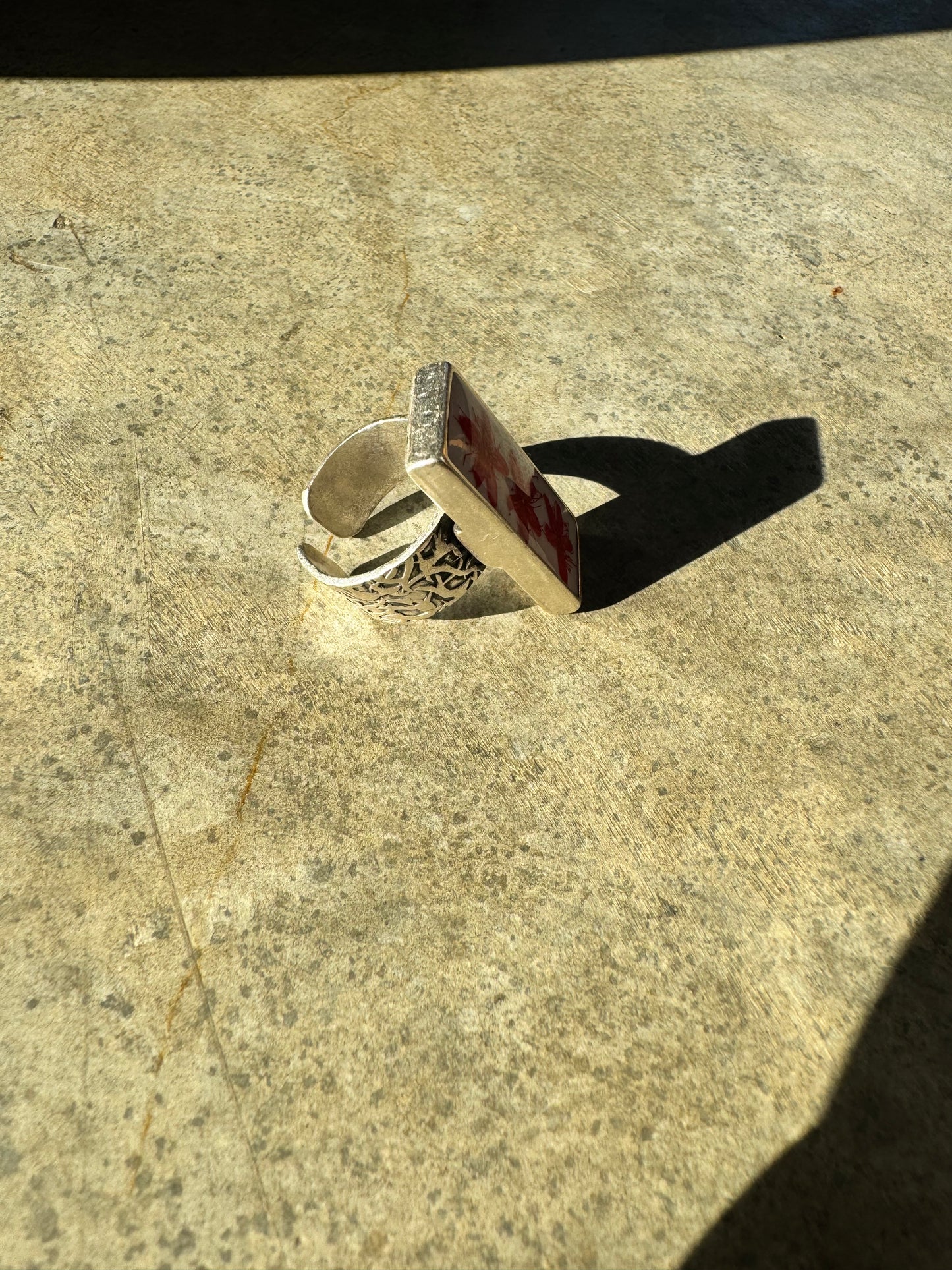 Rectangular long silver ring with red flower on a white background