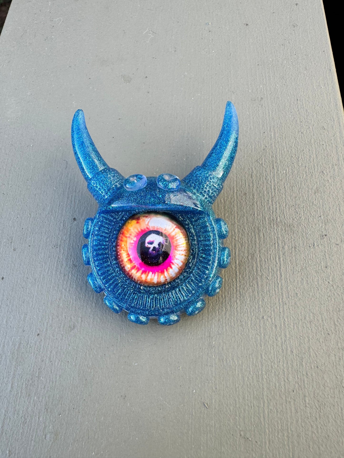 Blue monster brooch with pink skull iris. Model Vicky.