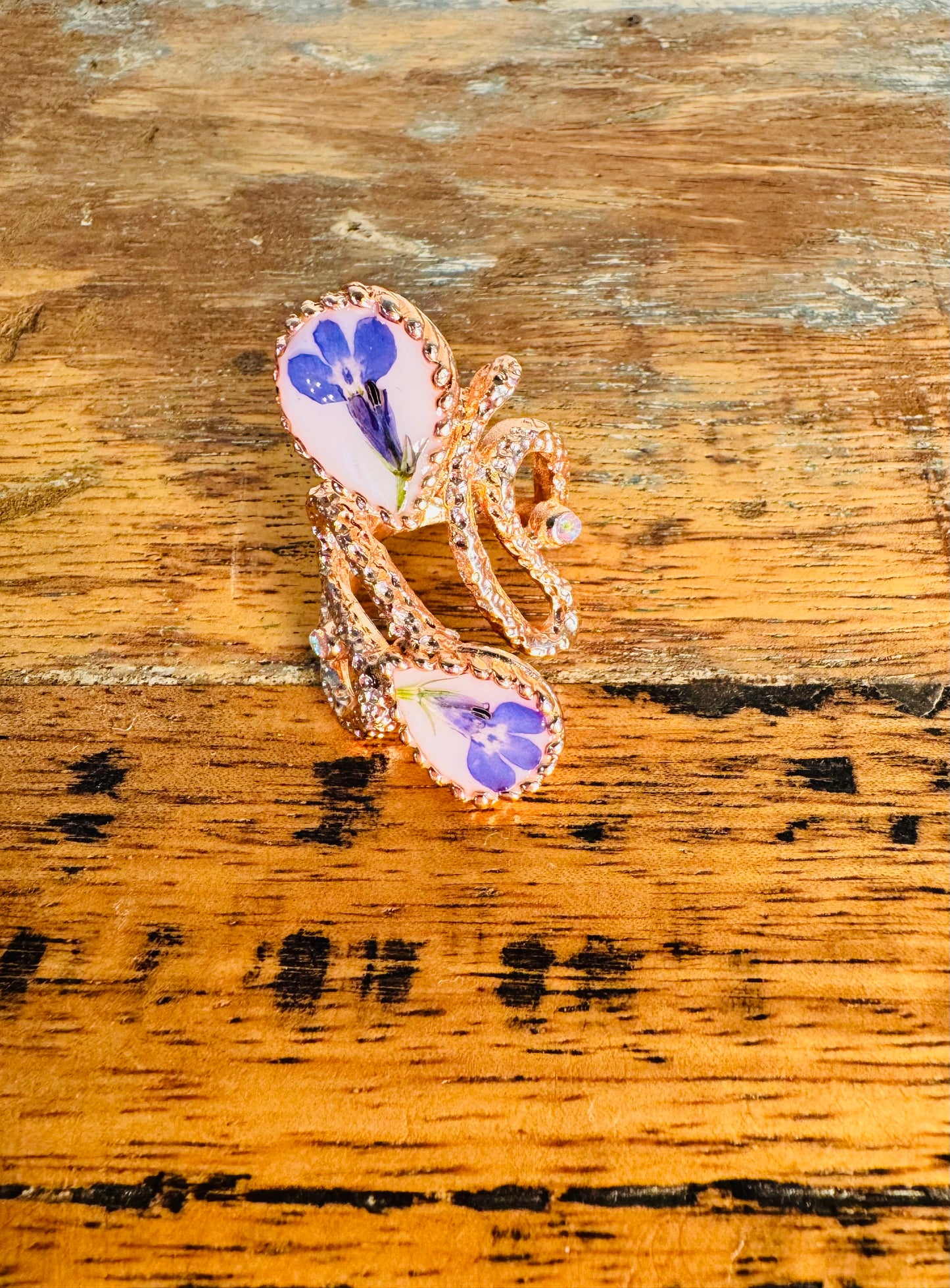 Oversized pink gold plated ring with blue flowers on a white background