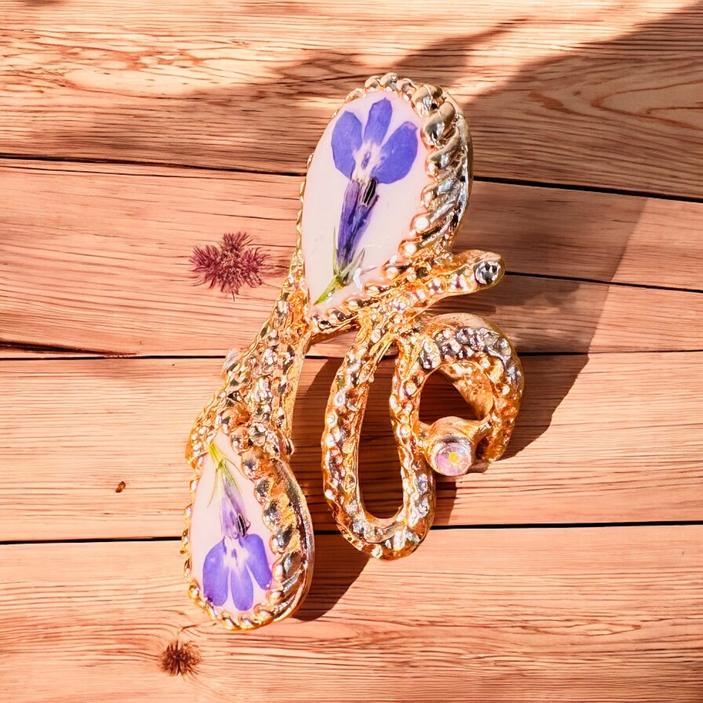 Oversized pink gold plated ring with blue flowers on a white background