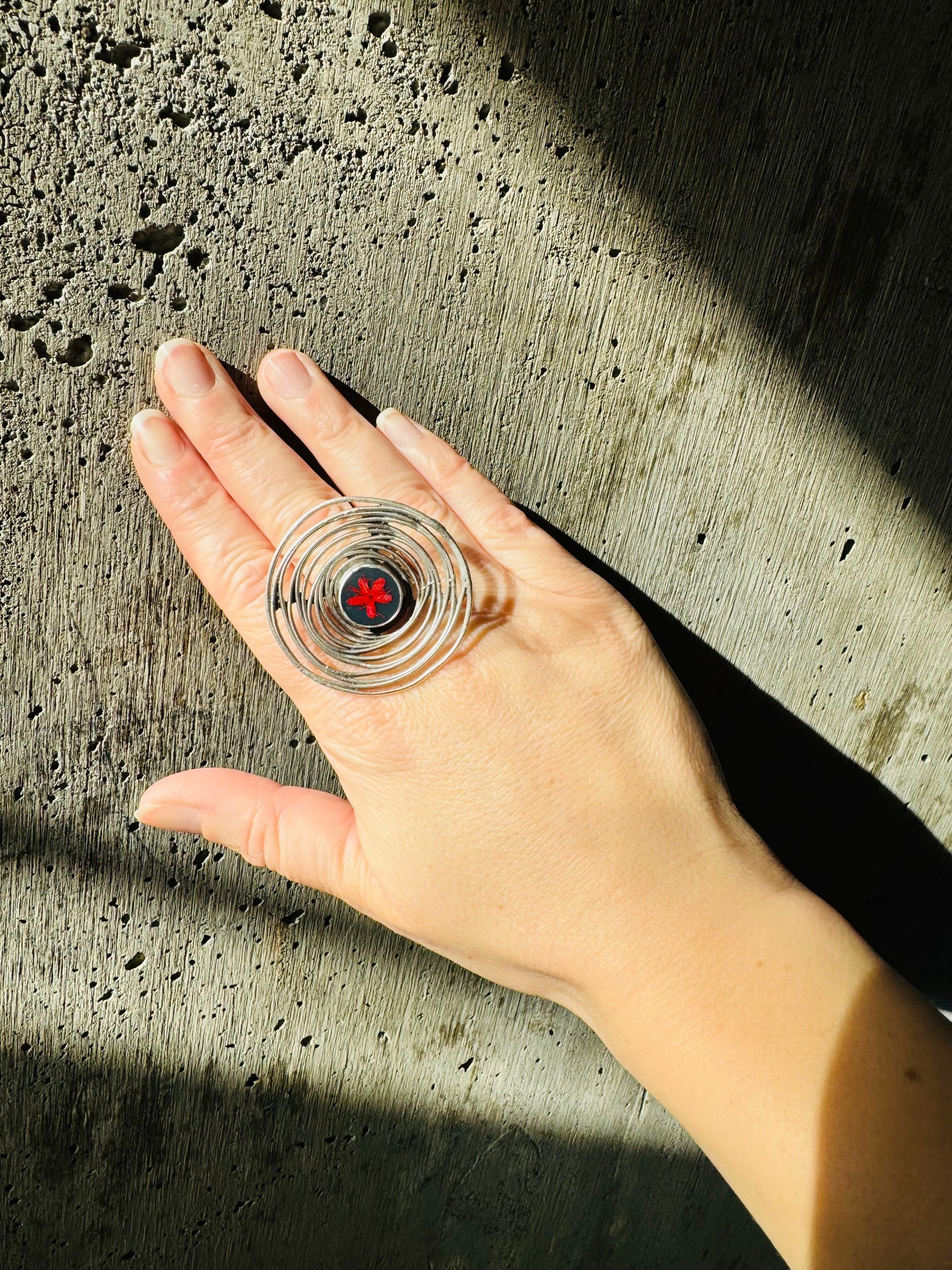 Oversized spiral silver ring with red flower on a navy background