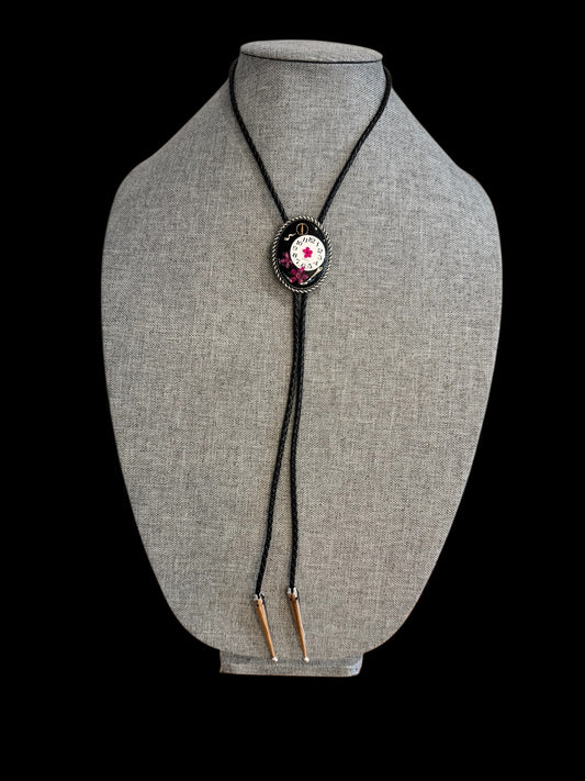 Bolo tie, pink flower and watch gears on black background