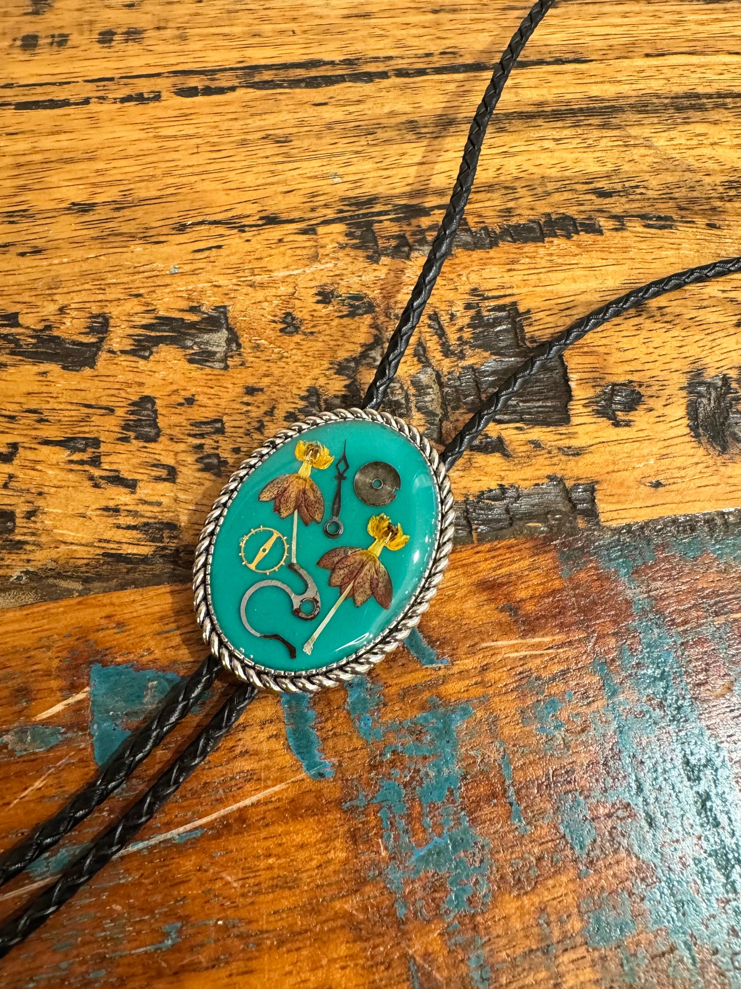 Bolo tie, red and yellow flowers and watch gears on a green background