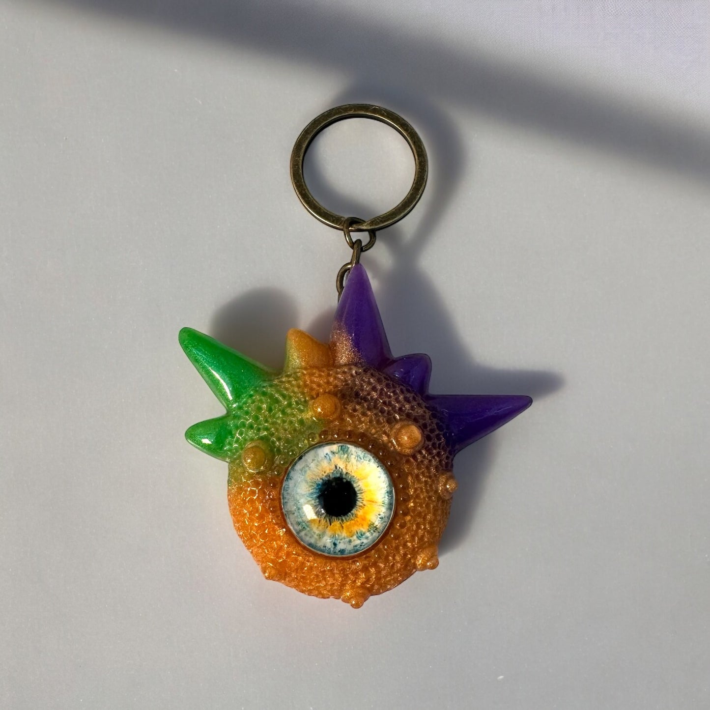 Creepy Monster Eye keychain, Orange, purple and green. Model Spiky.