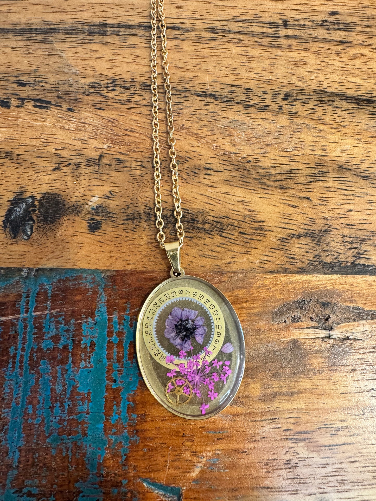 Oval necklace with purple and pink flowers and watch parts