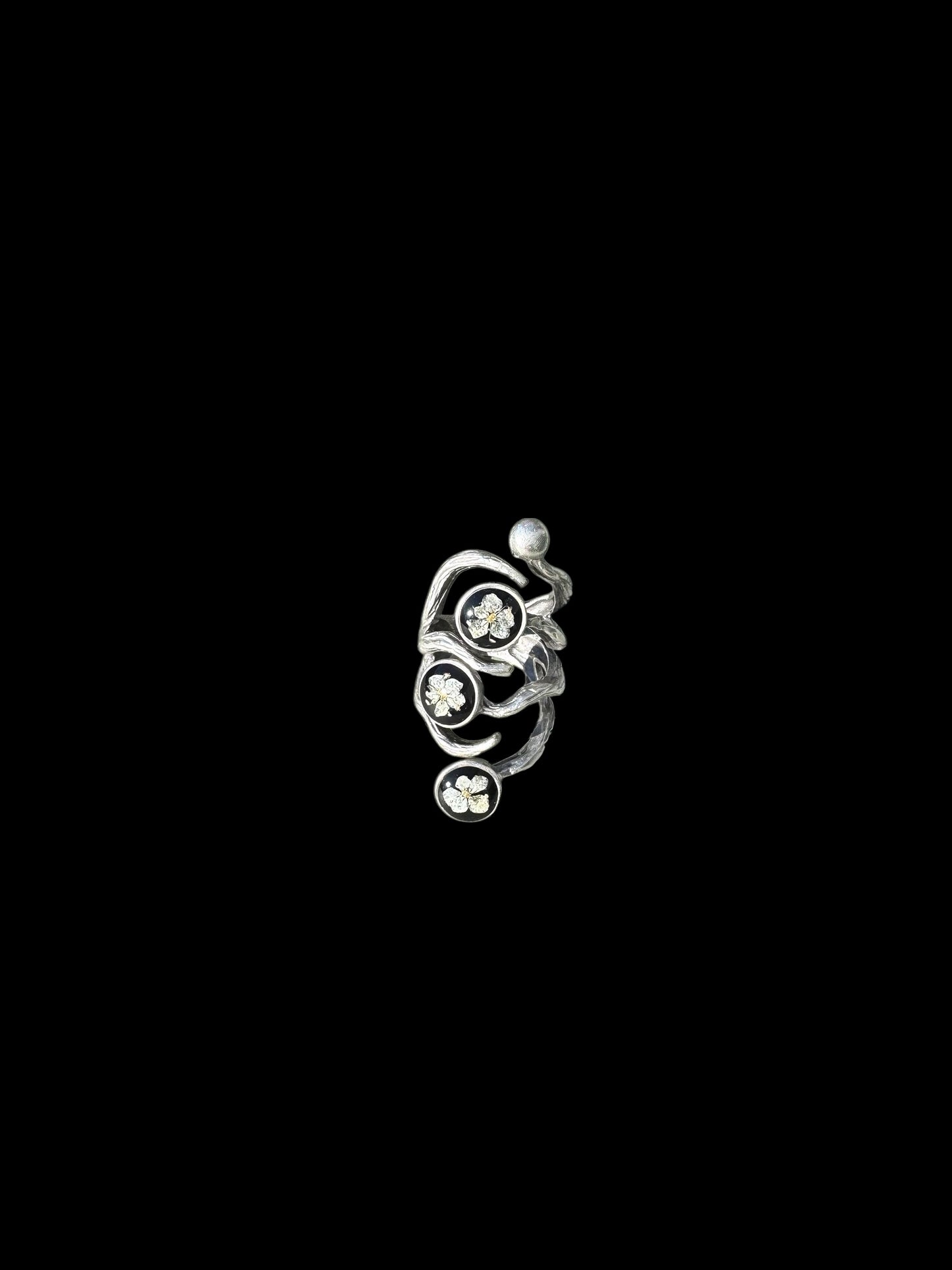 The roots ring with three white flowers on black background