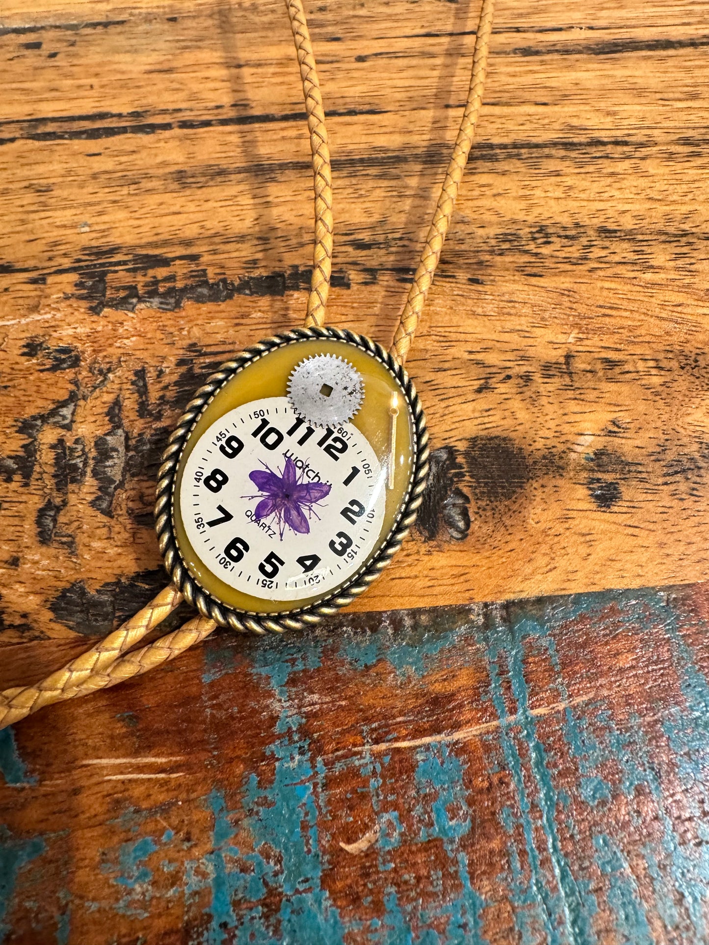 Bolo tie, purple flower and watch gears on gold background