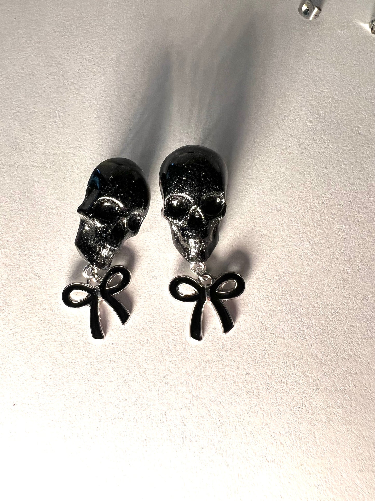 Skull with black bow and silver metal earrings studs