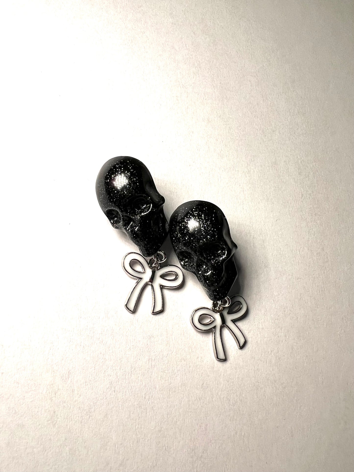 Skull with white bow and silver metal earrings studs