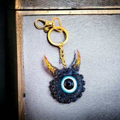 Black and gold one eyed monster keychain. Model Vicky.