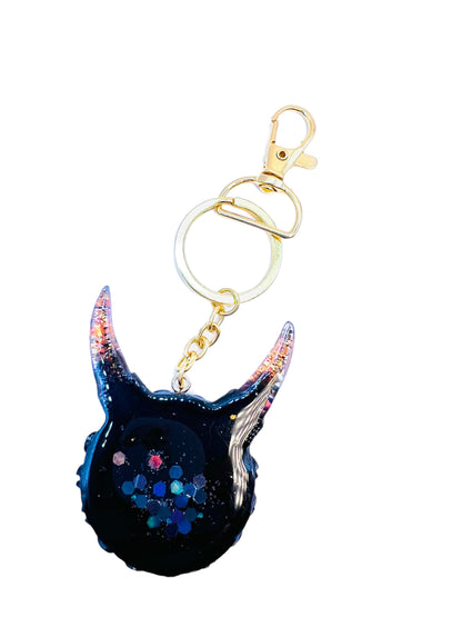 Black and gold one eyed monster keychain. Model Vicky.