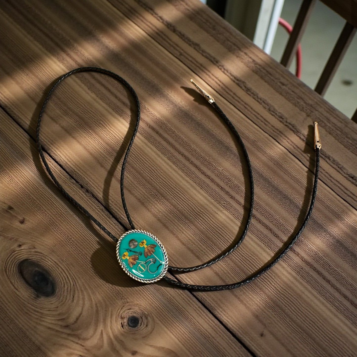 Bolo tie, red and yellow flowers and watch gears on a green background