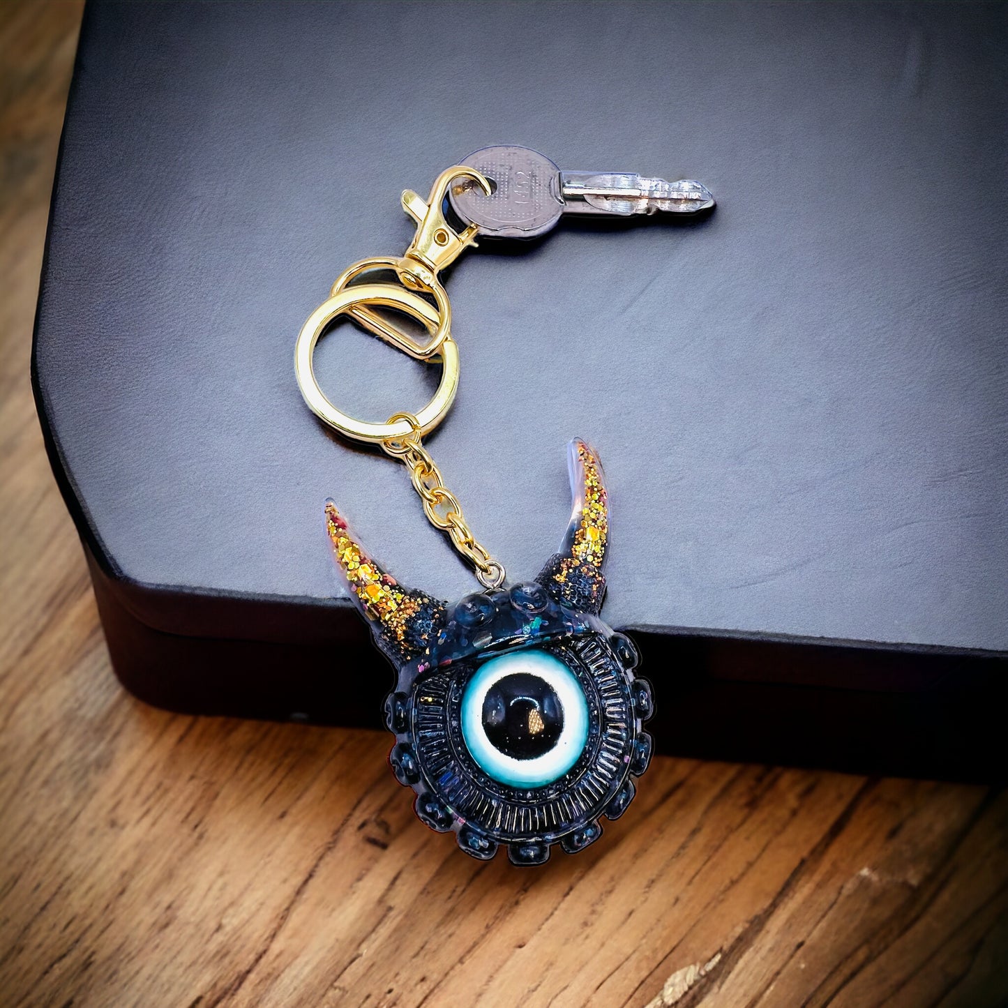 Black and gold one eyed monster keychain. Model Vicky.